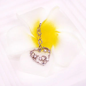 Macro detail of silver heart nipple ring with moon and star zircon inlay on white flower