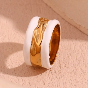 Macro detail of wide white ceramic ring with textured golden hammered metal inlay