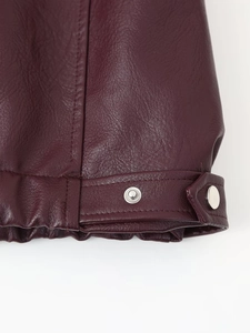 Detail of burgundy PU leather jacket cuff with adjustable strap and metal button snap closure