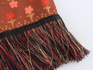 Detail of floral ethnic skirt featuring knotted tassels and intricate woven fringes