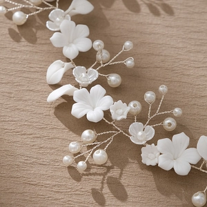 Close-up of bridal headband with white ceramic flowers, pearls and silver wire weaving