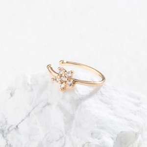 Detailed view of a gold-tone flower ear cuff with sparkling zircons on white marble