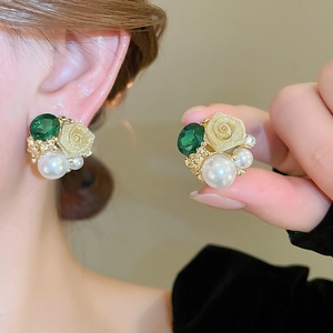 Détail d'une boucle d'oreille fleurie avec cristal vert, rose dorée et perles