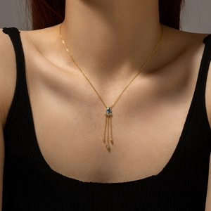 Detailed shot of golden tassel necklace with blue gemstone and fine dangling pendants
