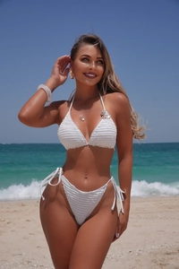 Detailed shot of white textured bikini set with silver flower charm on a sunny beach
