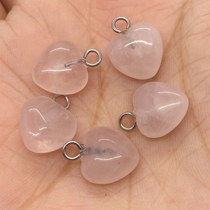 Handheld shot of five pink heart-shaped quartz stone pendants with metal rings