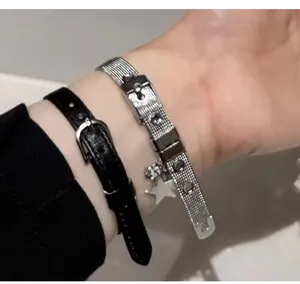 Détail du pendentif étoile Y2K sur bracelet en maille argentée et cuir noir