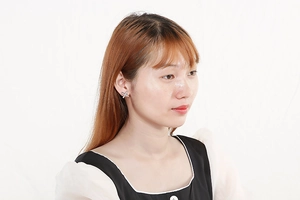 Close-up of a silver X-shaped earring with micro-inlaid zircons on a female model
