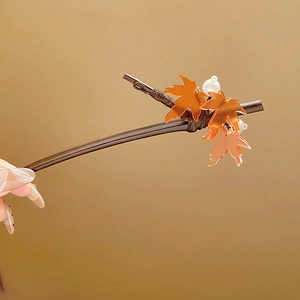 Close-up of wood hair stick featuring orange maple leaves and white pearl details