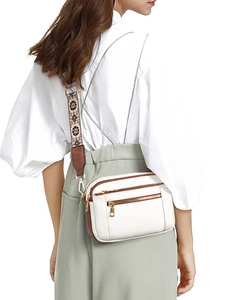 Detail of white PU crossbody bag featuring ethnic floral strap and golden zipper hardware