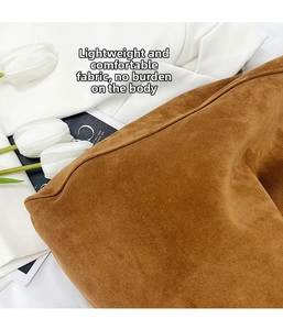 Close-up of brown suede tote bag texture with white tulip and elegant blazer background