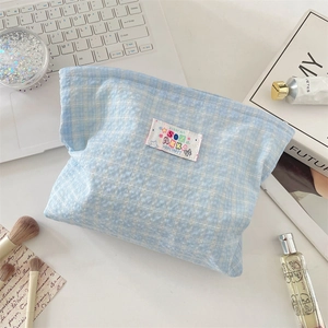 Vista piatta di una borsa cosmetica a quadretti azzurri in tessuto a nido d'ape