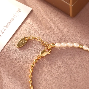 Elegant gold knot bracelet with white pearls and a handmade tag on pink leather background