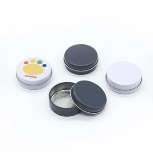 Close-up of small round metal tins in white and dark grey for solid balm storage