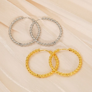 Detail of large twisted hoop earrings in gold and silver finish on silk fabric