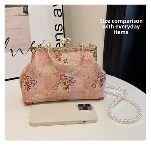 Detail view of pink floral embroidery clutch with pearl handle and smartphone for size scale