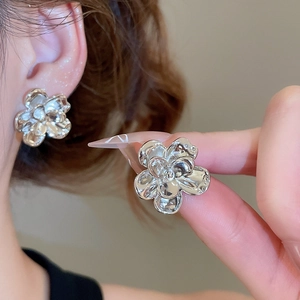 Close-up of silver flower stud earrings showing metallic texture and floral design