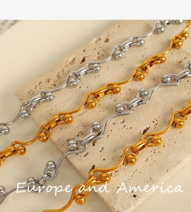 Detailed shot of gold and silver wavy bead chains on a beige stone display stand