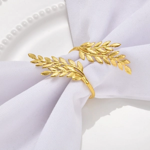 Golden wheat ear metal napkin ring on white cloth napkin and beaded plate decoration