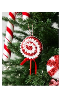 Close-up of red glitter Christmas lollipop ornament hanging on a green tree branch