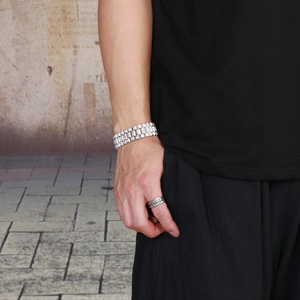 Close-up of a silver iced-out multi-row hip hop bracelet and vintage rings on model