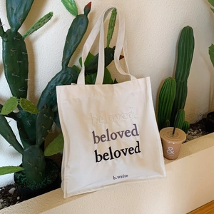 Detail of beloved letter embroidery on cream canvas tote bag with long handles