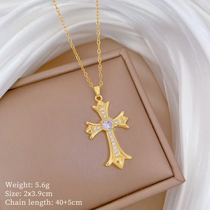 Detailed view of micro-inlaid gold cross pendant with cubic zirconia on a jewelry box