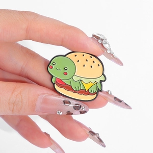 Cute turtle burger enamel pin accessory for backpacks and clothes shown in hand