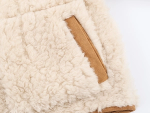 Detail of cream sherpa fleece texture with brown suede pocket trim on jacket