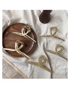 Detailed collection of five golden metal hair claws on a wood tray and white fabric