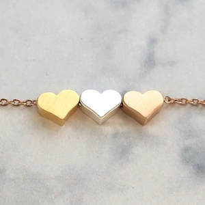 Three-tone heart pendant necklace with gold, silver, and rose gold finishes on a fine chain
