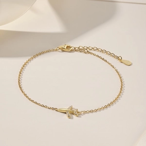 Detail of S925 silver gold bracelet with a plane pendant and white zircon accents