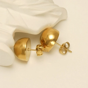 Detailed view of gold semi-sphere stud earrings with a high-shine mirror finish surface