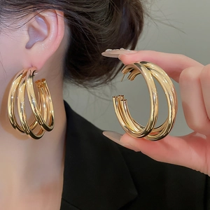 Macro shot of large multi-layer gold round earrings highlighting shiny metallic texture