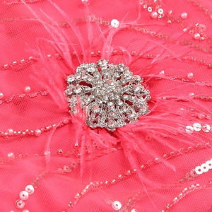 Close-up of hot pink evening gown with sequins, pearls, feathers and rhinestone brooch