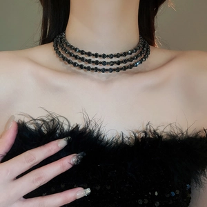 Detailed close-up of a triple-layered black faceted bead choker necklace on a model