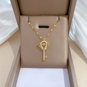Luxurious gold crown key pendant necklace with sparkling crystals on beige jewelry box