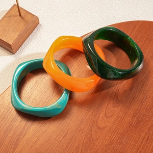 Detailed macro of three resin bangles with marble texture on a wooden surface