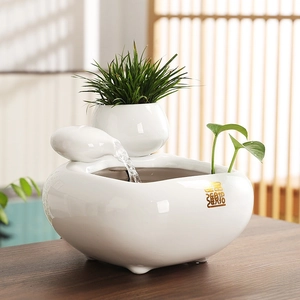 Detail of white ceramic indoor fountain with golden Lucky symbol for office desktop decor