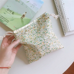 Close-up of floral cotton drawstring pouch on a wooden desk with a notebook