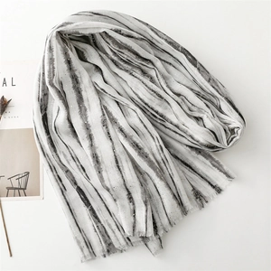 Close-up of marble pattern scarf with gold foil details and frayed edges on linen texture