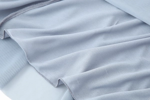 Detailansicht der hellblauen Mesh-Stoffstruktur und des Wellensaums am Maxikleid