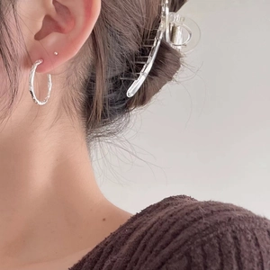 Close-up of silver circular earrings with unique hammered texture on a model's ear