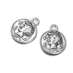Macro shot of two round antique silver coin pendants with embossed classical portraits