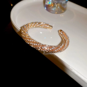 Close-up of gold threaded open bangle with pavé crystals on a white ceramic tray