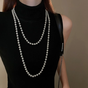 Detailed view of layered long faux pearl necklace on black turtleneck for a French style