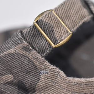 Détail macro d'une casquette en coton camouflage avec boucle métallique réglable en bronze