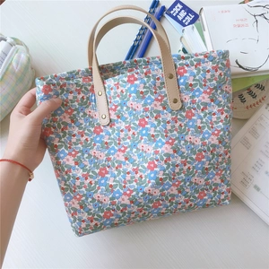 Dettaglio della borsa tote in cotone floreale con manici in pelle e rivetti in metallo