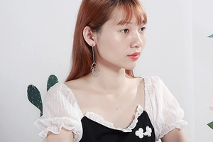 Boucles d'oreilles pendantes visage en argent avec chaîne portées par un mannequin