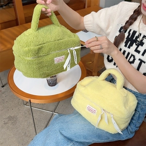 Detail of two plush makeup bags in green and yellow with fluffy texture and ribbon